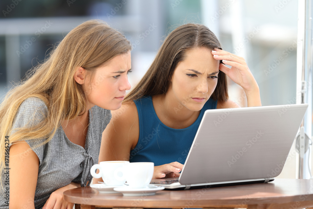 Two worried friends watching media content on line Two worried friends watching media content on line