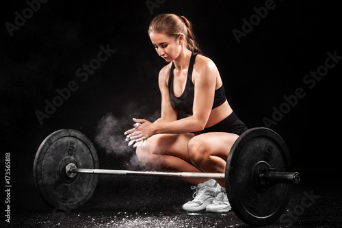Sporty fitness woman getting ready for crossfit training with barbell. Crossfit workout motivation.