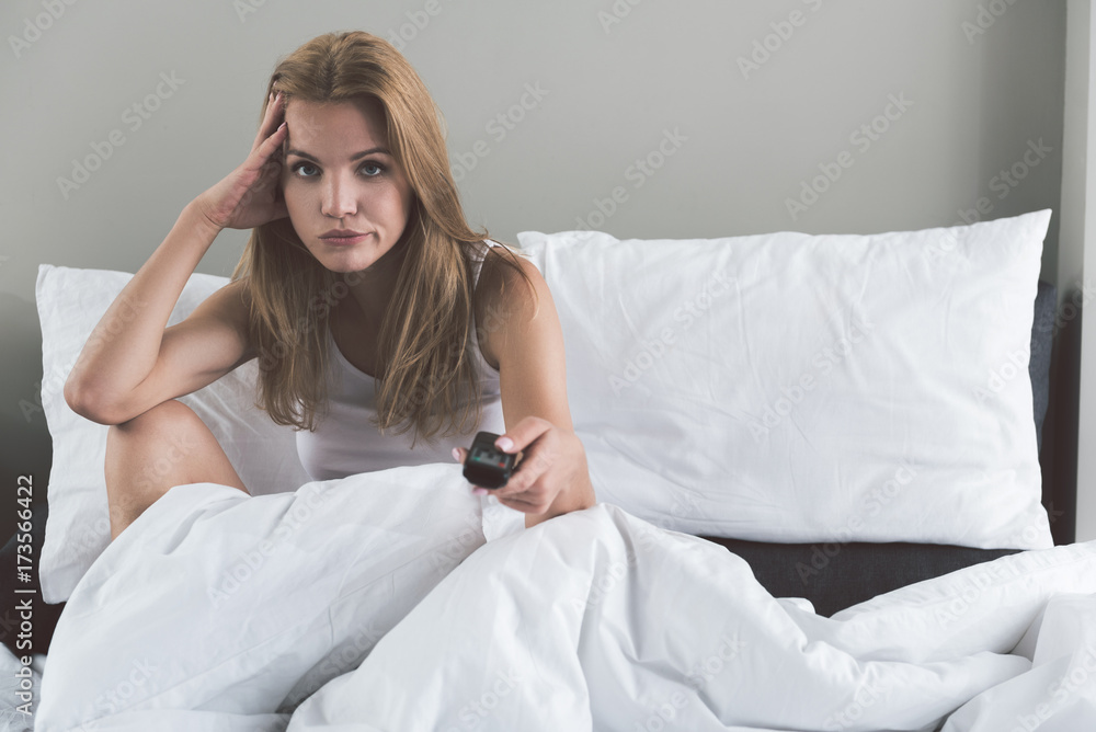 Sad young woman sitting on bed with boredom Sad young woman sitting on bed with boredom