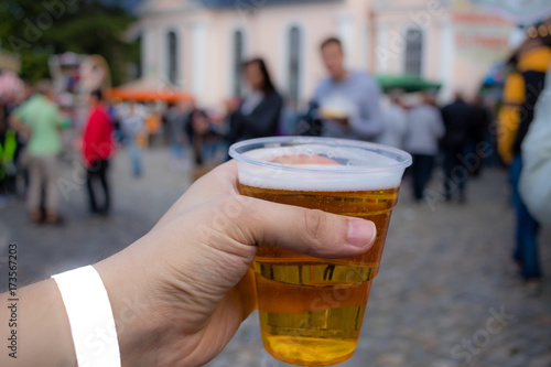 Man Holding Beer in plastic cup with People in background