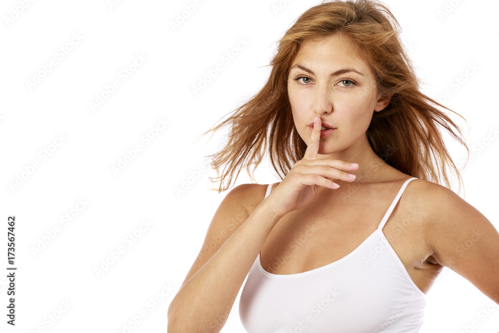Young beautiful blonde woman has put forefinger to lips as sign of silence