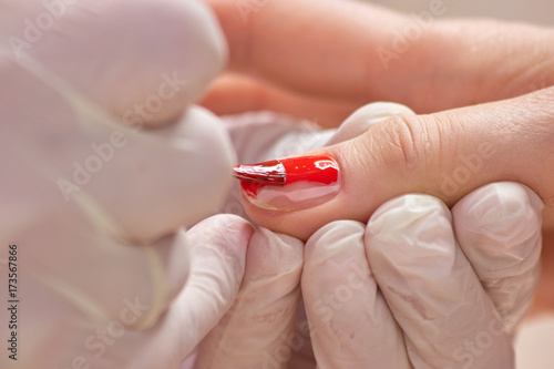 Фотография Manicurist applying red nail varnish