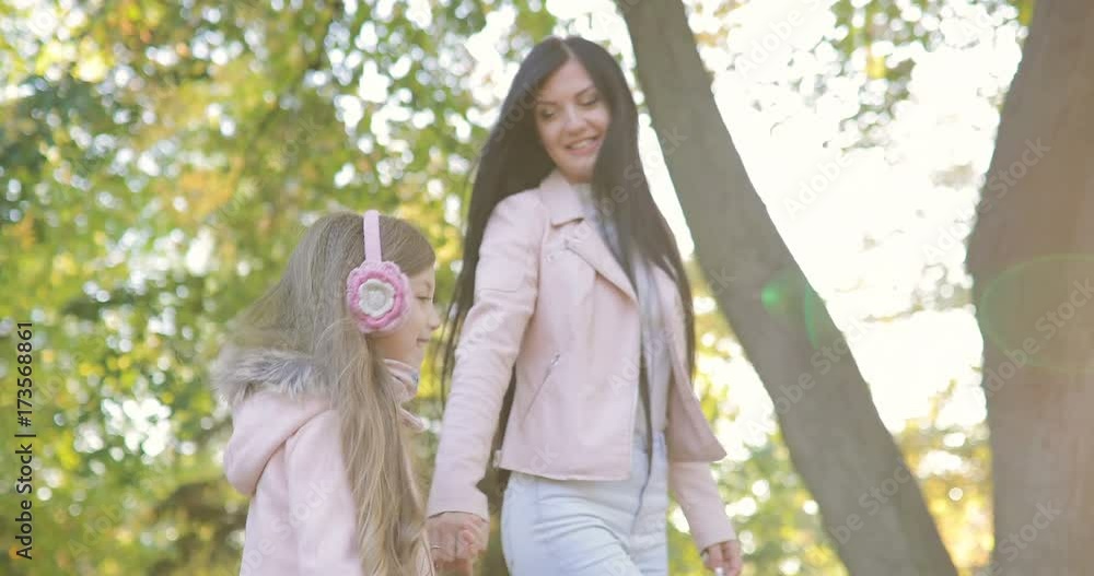 Young mother with her little daughter walking in the park Young mother with her little daughter walking in the park