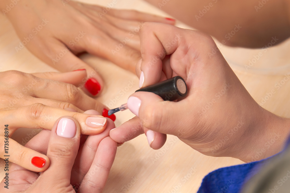 Manicurist doing manicure in nail salon. Beautician applying nail polish to female nail in a salon. Nail salon and spa. Manicurist doing manicure in nail salon. Beautician applying nail polish to female nail in a salon. Nail salon and spa.