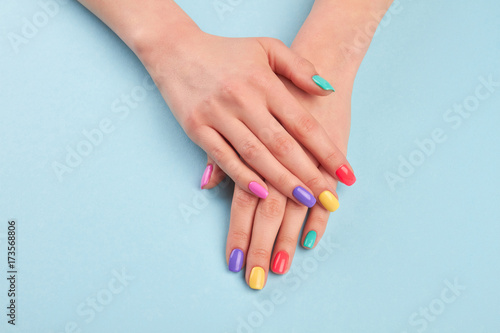 Female beautiful manicured hands. Woman hands with stylish colorful nails on light blue background. Skin and nail care.