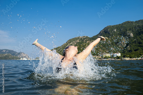 Woman happy jump sea waves splash in tropics on vacation.