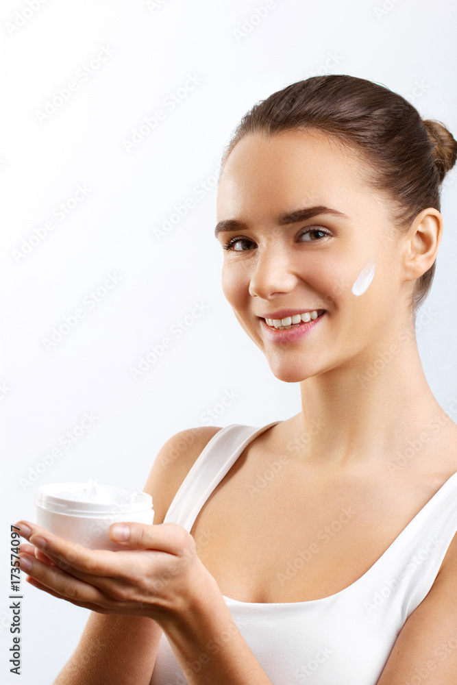 Woman Face Skin Care. Portrait Of Attractive Young Female Applying Cream Holding Bottle. Closeup Of Smiling Girl With Natural Makeup And Fresh Skin. Beauty Cosmetics. High Resolution Woman Face Skin Care. Portrait Of Attractive Young Female Applying Cream Holding Bottle. Closeup Of Smiling Girl With Natural Makeup And Fresh Skin. Beauty Cosmetics. High Resolution