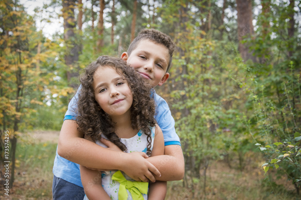 In the autumn forest, the brother hugs a cute little curly sister. In the autumn forest, the brother hugs a cute little curly sister.