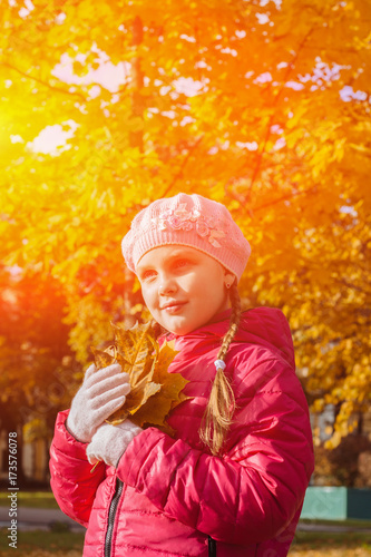 Adorable little girl in autumn park with leaves  collecting autumn bouquets of colorful fallen foliage  Autumn composition  bouquet of brightly colored red orange and yellow maple leaf. Toned