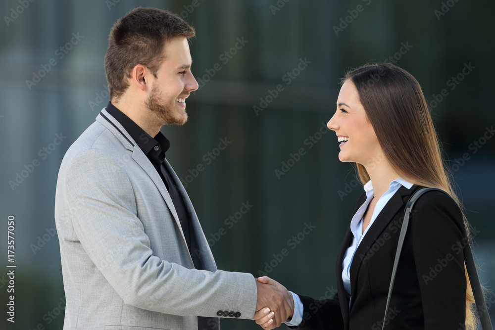 Happy executives meeting and handshaking on the street
