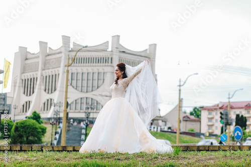 Happy young bride in white dress posing in the city
