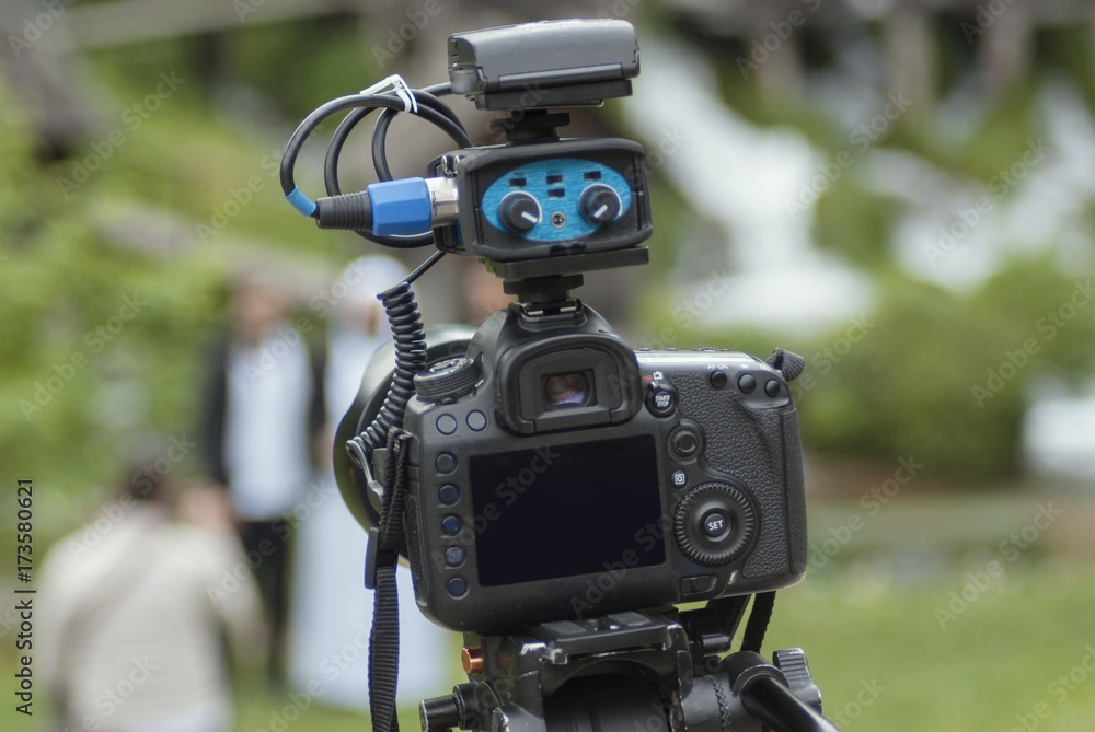 Modern camera with mic on tripod recording nature