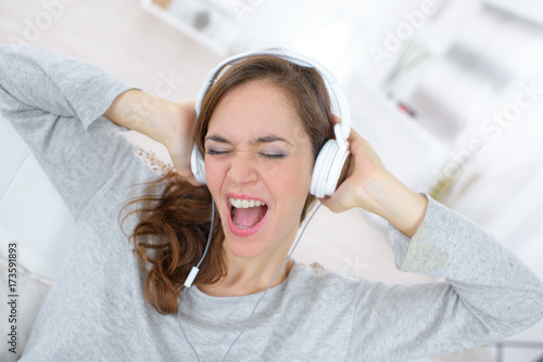 young woman listening to music on headphones and sings