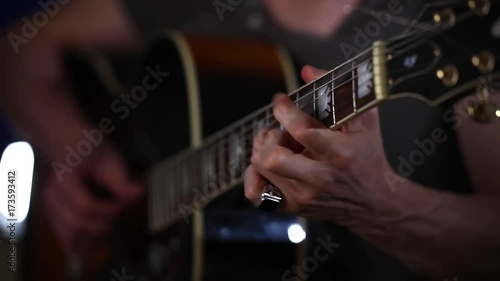 Playing acoustic guitar side angle close up strumming left hand in focus left hand  photo