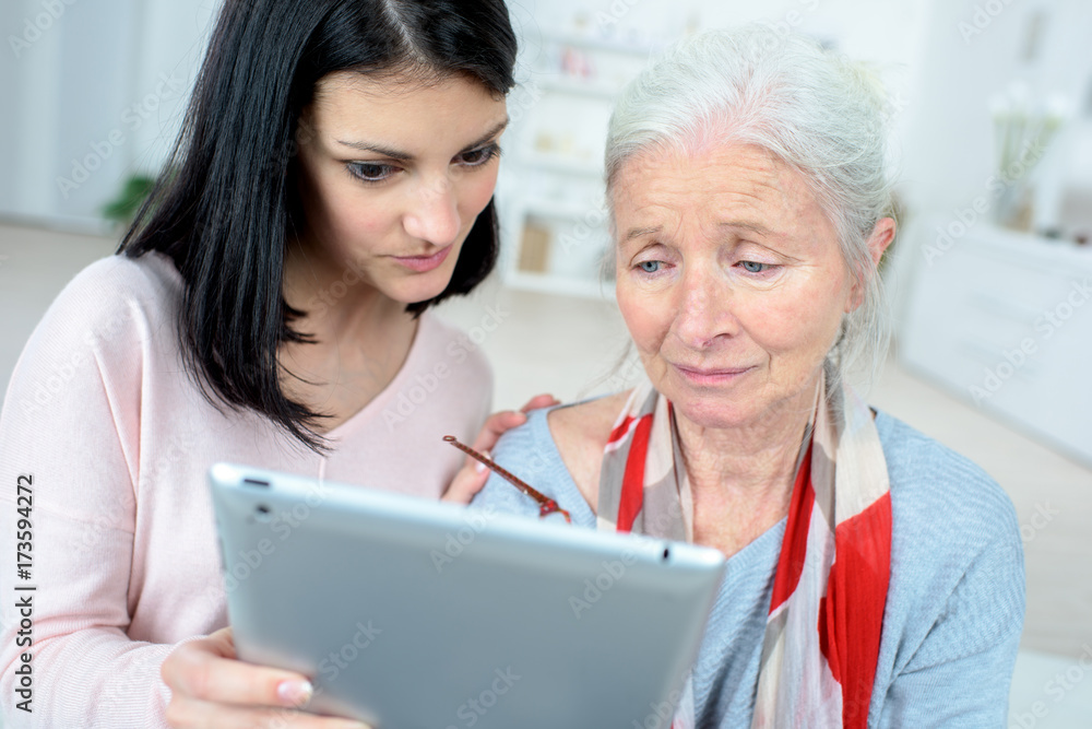helping old woman use a tablet computer helping old woman use a tablet computer