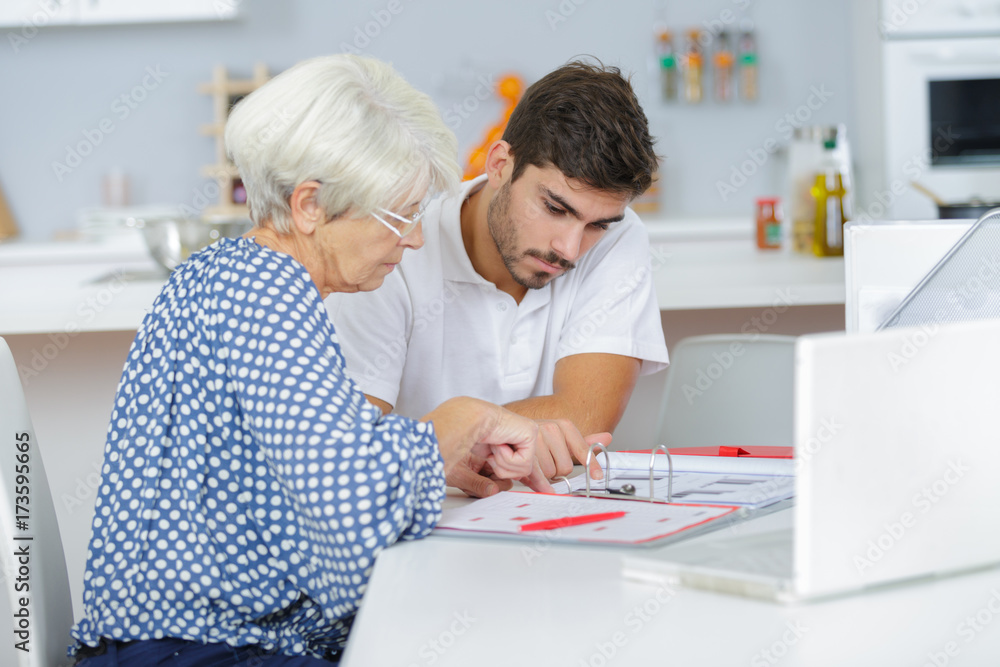 Fototapeta premium handsome young lad helping senior lady with her taxes