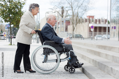 senior woman pushing husband in wheelchair