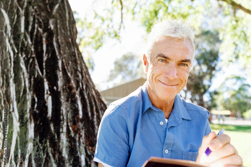 Senior man sittingin park while reading book Senior man sittingin park while reading book