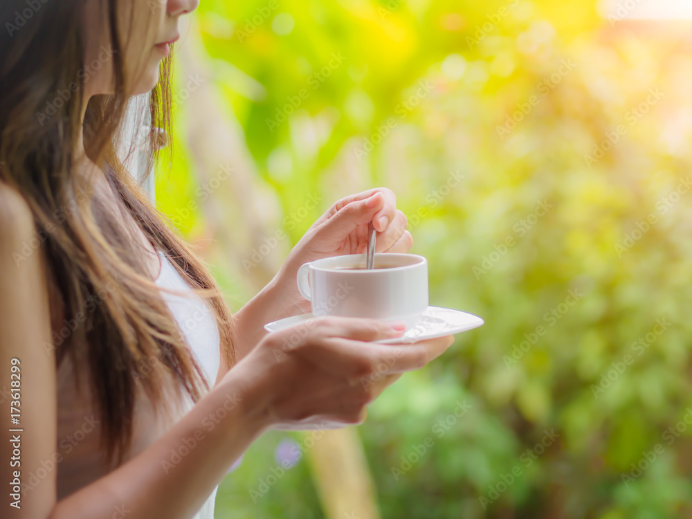 Beautiful asian female drinking a cup of coffee at the gaerden in the morning, with selective focus. Relaxing and healthy concept. Beautiful asian female drinking a cup of coffee at the gaerden in the morning, with selective focus. Relaxing and healthy concept.