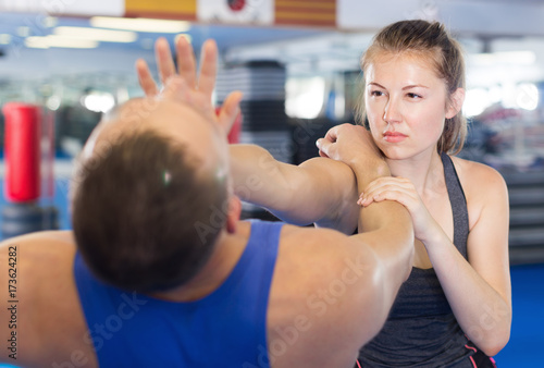 Woman and trainer practicing punches in gym