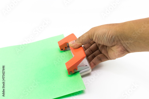 Man hand does using an orange paper punch with green paper isolated