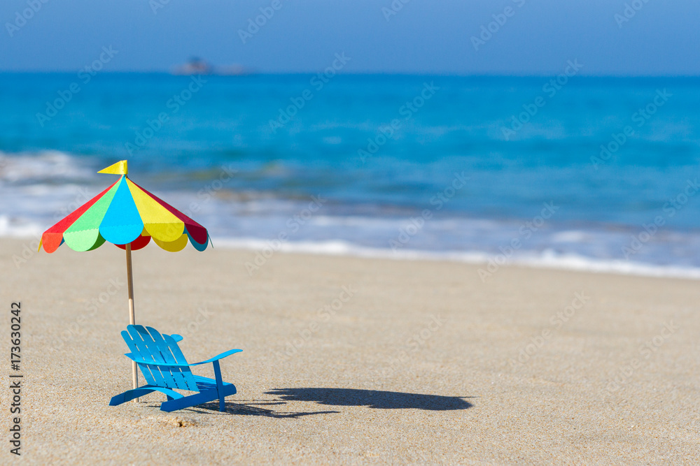 beach umbrella and chair made from paper standing on sand on background of blue ocean. The hot climate. Handmade. beach umbrella and chair made from paper standing on sand on background of blue ocean. The hot climate. Handmade.