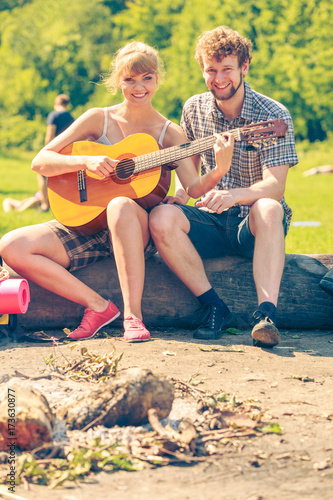 Young couple camping playing guitar outdoor