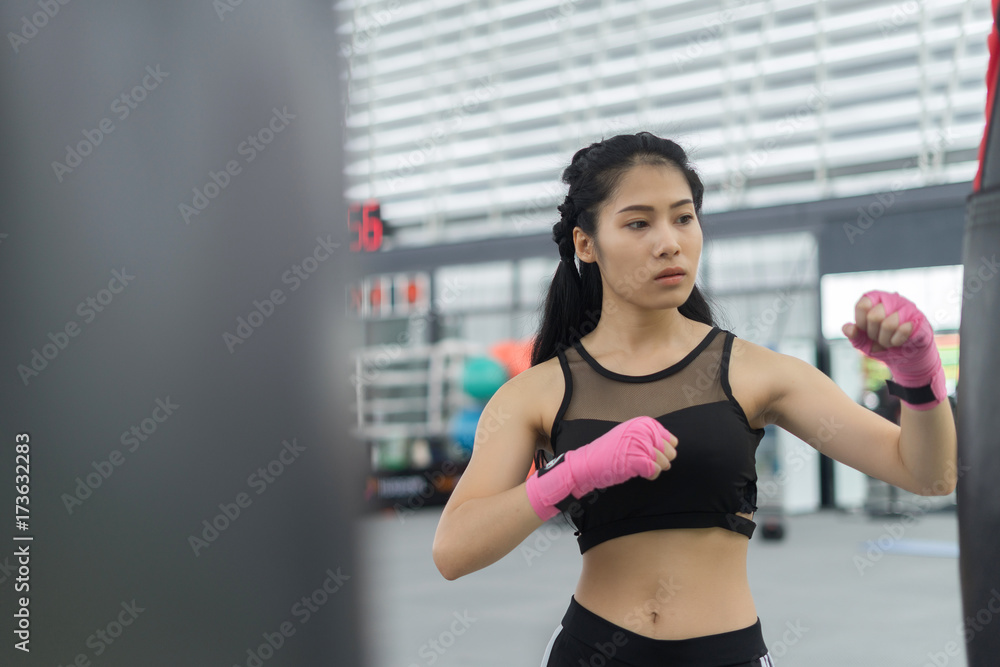Fitness woman in training showing exercises with doing kickboxing in gym