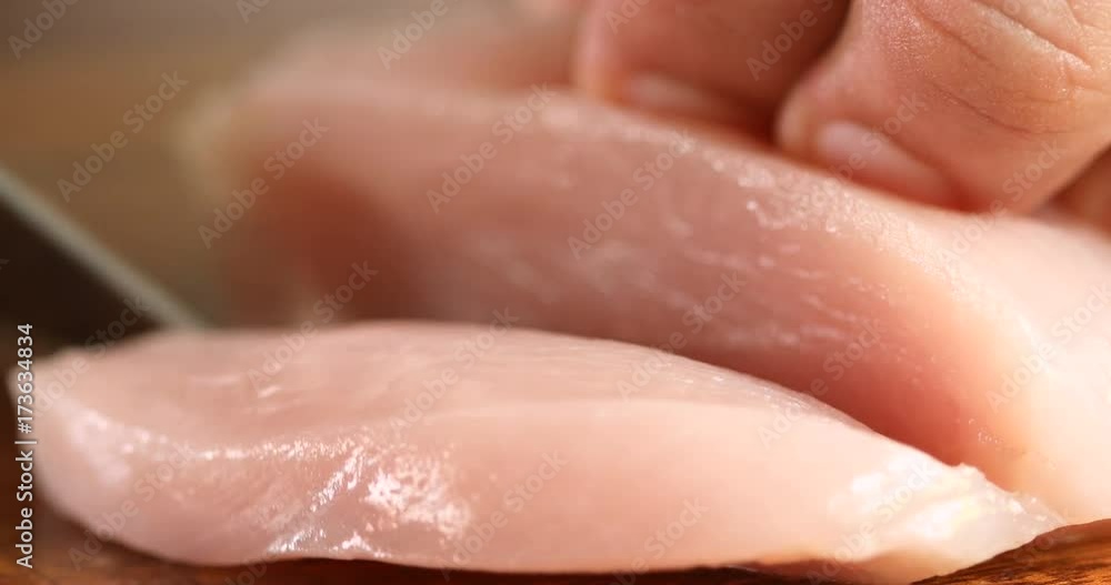 Extremely Close up the human hand cutting raw chicken meat on wooden chop board in kitchen room , 4K Dci resolution Extremely Close up the human hand cutting raw chicken meat on wooden chop board in kitchen room , 4K Dci resolution