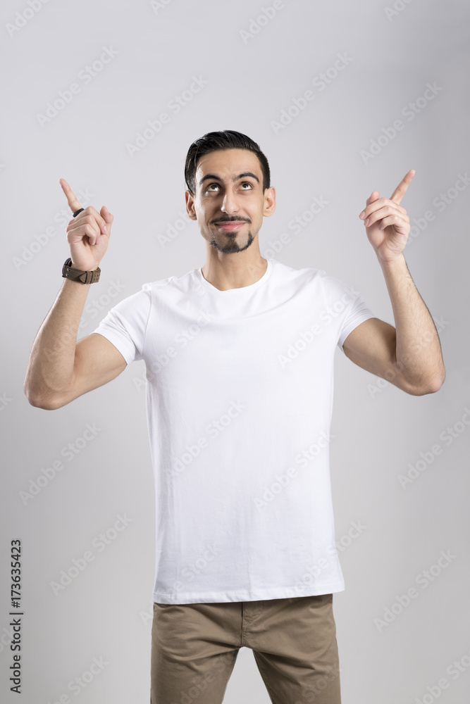 Dark-Haired Young Man in Casual Wear Pointing Fingers Upwards Dark-Haired Young Man in Casual Wear Pointing Fingers Upwards