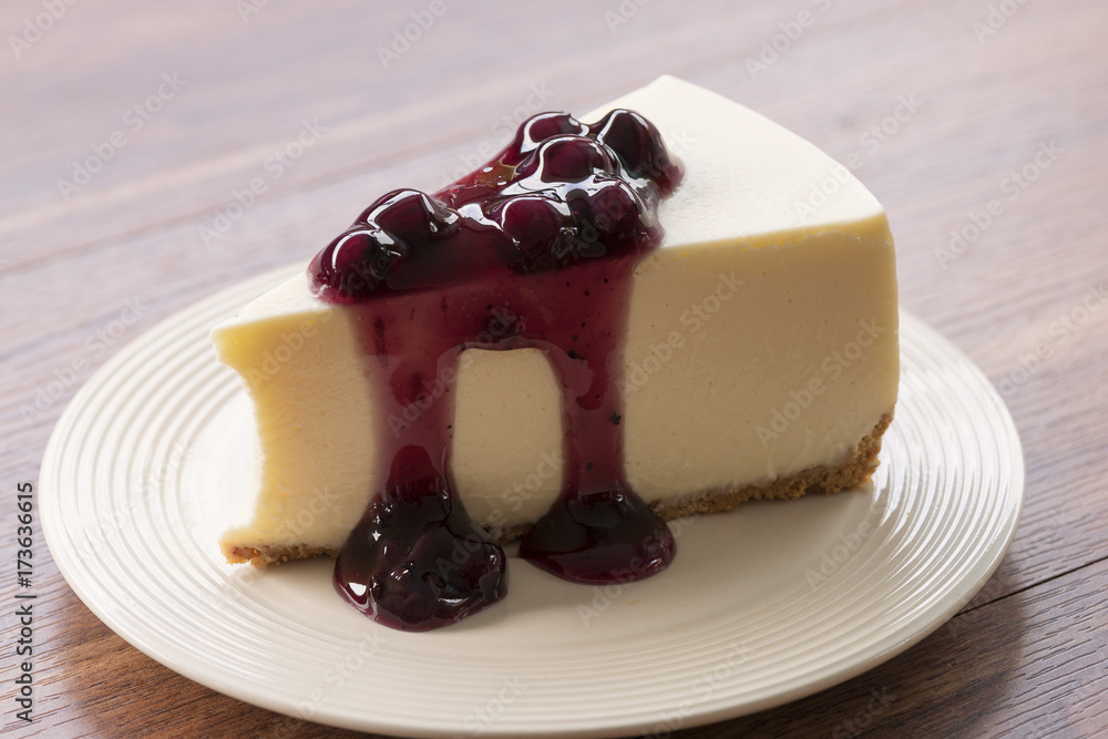 Blueberry cream cheesecake in white plate on wood table Blueberry cream cheesecake in white plate on wood table