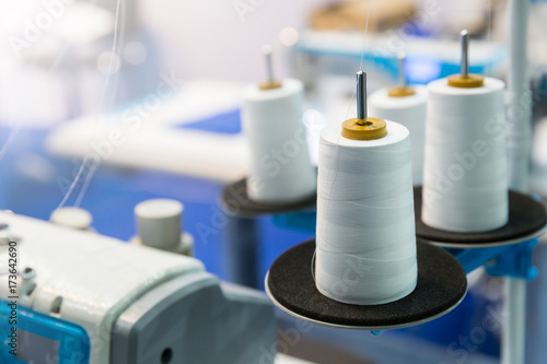 Spools of white threads on sewing machine, closeup