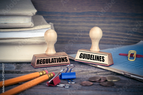 Regulations and Guidelines concept. Rubber Stamp on desk in the Office. Business and work background. photo