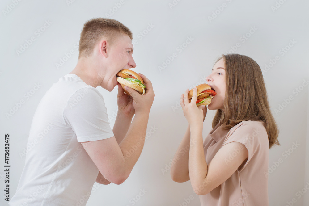 young couple with hamburgers on white background young couple with hamburgers on white background