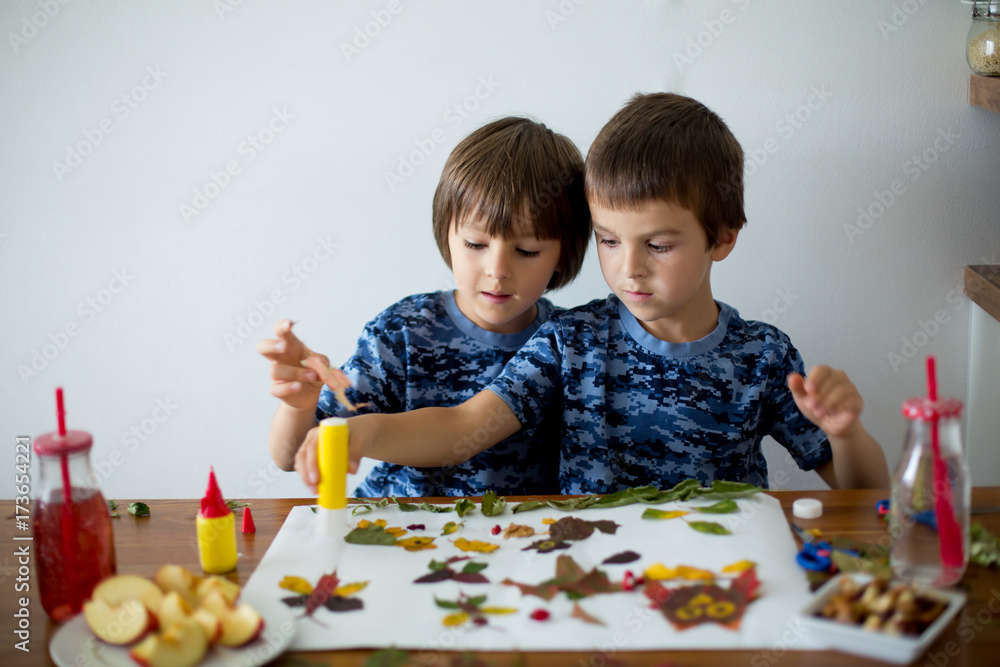 Sweet children, boys, applying leaves using glue Sweet children, boys, applying leaves using glue