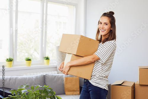 Young woman moving into new apartment holding cardboard boxes with belongings