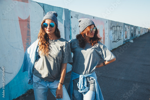 Models wearing plain tshirt and sunglasses posing over street wall