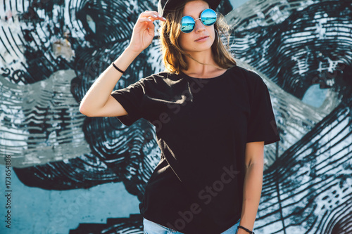 Model wearing plain tshirt and sunglasses posing over street wall