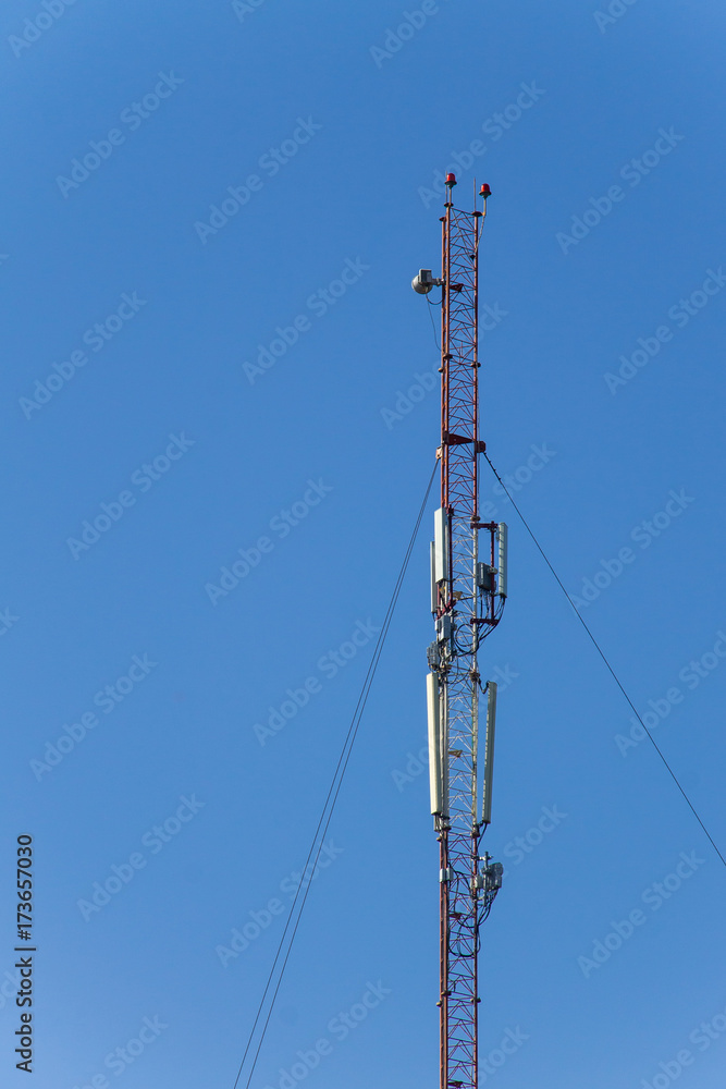 Metal tower with antennas for mobile cell phone communications against blue sky
