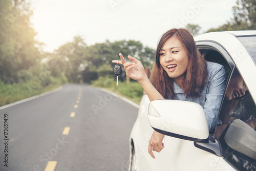 beautiful woman got new car. showing car key from window out of new car. photo