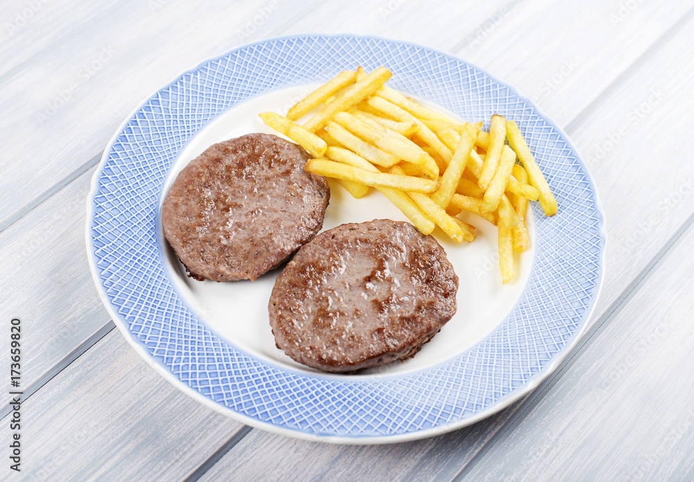 Hamburger with french fries on blue plate on wooden table. Food. Hamburger with french fries on blue plate on wooden table. Food.