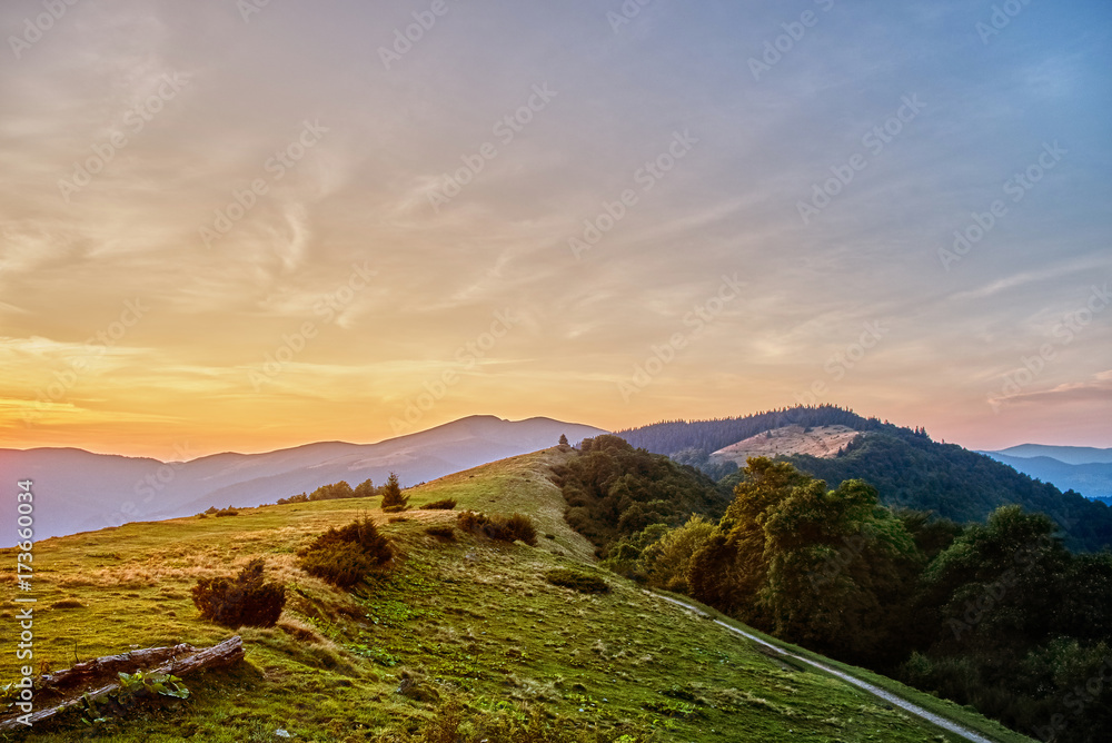 Fototapeta Green mountain peak on a background of beautiful sunset on a blue sky.