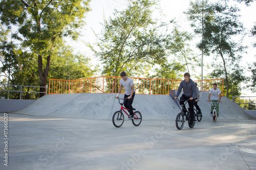 Group of young people with bmx bikes in skate plaza, stunt bicycle riders in skatepark 
