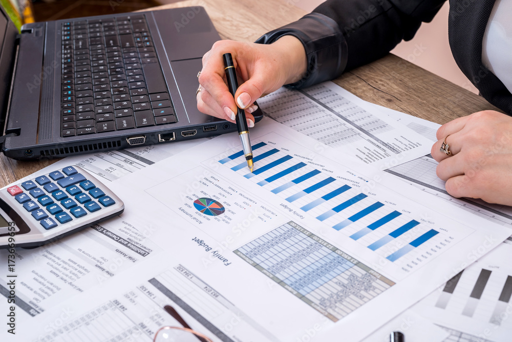Business woman account annual budget with laptop, pen and graph. Business woman account annual budget with laptop, pen and graph.