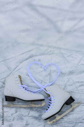 I love ice skating. Ice skates on rink background with lace in heart shape.