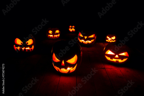 The concept of Halloween. Many glowing fiery light angry scary pumpkins. jack lantern in the dark, on a wooden background
