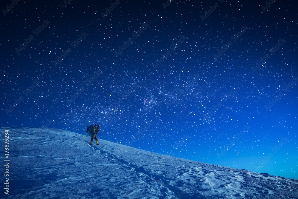 A hiker climbs up a snowy slope at night A hiker climbs up a snowy slope at night