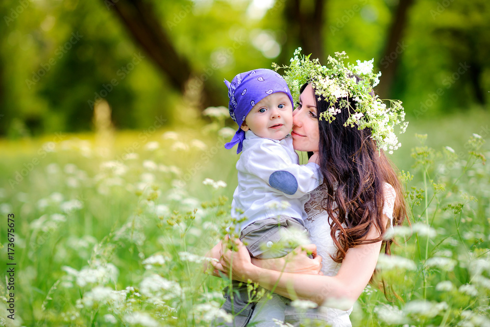 mom walks in the park with a beloved baby, on her mom's head a bouquet of wildflowers