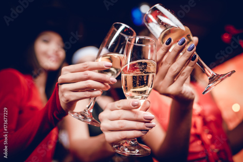 Halloween party. Three girls in suits posing with glasses of champagne in their hands