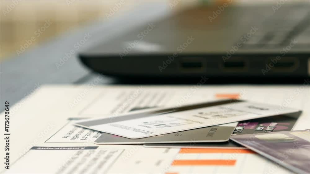 Motion view of golden bitcoin and credit cards on desk in office with laptop at background Motion view of golden bitcoin and credit cards on desk in office with laptop at background
